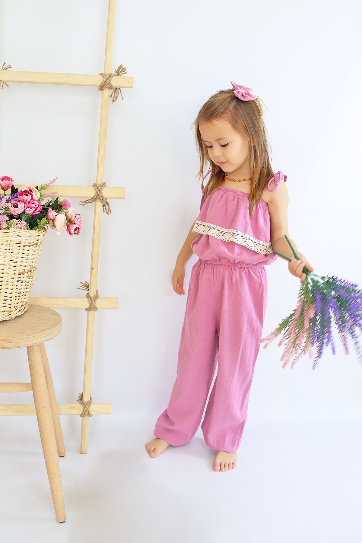 Jumpsuit Pera - Lila Jumpsuit mit Spitzendetails, schmalen Trägern und Haarspange